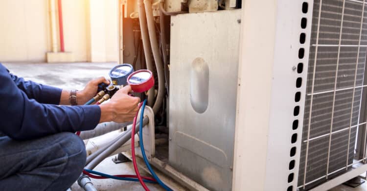technician working on HVAC unit for signs you need emergency hvac services blog