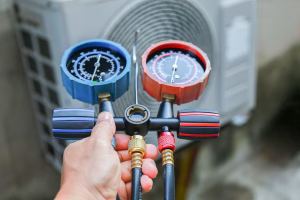 HVAC service technician using gauges to check refrigerant for Signs Your AC is Low on Refrigerant blog
