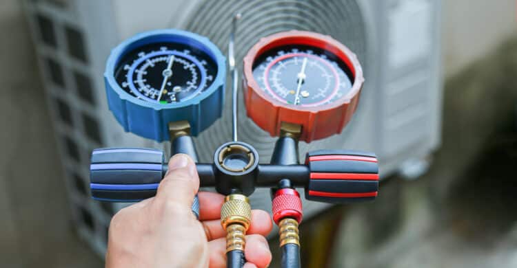 HVAC service technician using gauges to check refrigerant for Signs Your AC is Low on Refrigerant blog